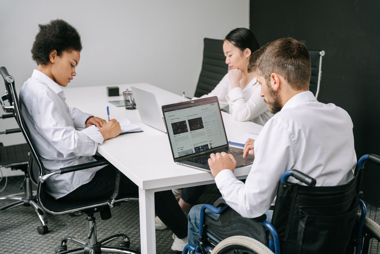Support professionals and a person who uses a wheelchair collaborating together at a table
